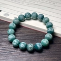 Close-up of green agate beads with carved Buddhist mantras on a wooden table - Imperial Green Carved Six Characters