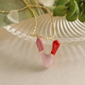 Vue macro d'un collier doré avec pendentif rouge à lèvres émaillé rose et rouge élégant - Style-V