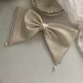 Detalle de un lazo de satén beige para el pelo con elegantes perlas blancas colgantes - Beige