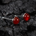 Macro shot of red round jade studs in silver bezel setting on dark rock texture background - Natural Red Agate Round Silver 5mm