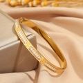 Brazalete dorado de acero titanio con circonitas brillantes sobre fondo de seda de lujo - Patrón de Cruz Dorado
