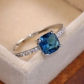 Close-up of square blue sapphire ring with micro-pave zircon on silver band - Peacock Blue