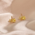 Macro detail of golden rhino stud earrings with yellow gemstone on champagne silk - Triceratops / Yellow