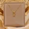 Detailopname van een 18K vergulde titanium ketting met een roze zirkoon vlinderhanger - Goud + Roze