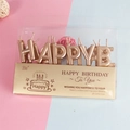 Detailed view of gold Happy Birthday letter candles in premium clear plastic packaging - Champagne Gold
