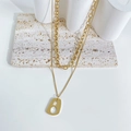 Double layered gold titanium necklace with geometric pendant on white stone display - Gold