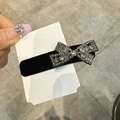Detailansicht der schwarzen Samt-Haarspange mit funkelndem Strass-Schleifen-Design - Schleife