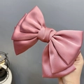 Elegant dusty rose satin bow hair clip held by hand showing smooth silky texture - Spring Clips / Korean Pink