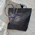 Close-up detail of vintage denim tote bag with colorful beaded straps and gold logo - Blue-Pink Strap