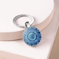 Macro detail of mandala glass dome keychain with purple floral pattern on silver base - Style 3