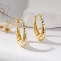 Elegant gold-tone croissant hoop earrings displayed on white stone with dried flowers - Gold