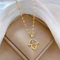 Detail view of a gold Hamsa hand necklace with blue and clear stones on a lip chain - F432 Titanium Steel Chain Copper Pendant