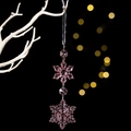 Dettaglio di un ornamento a fiocco di neve in acrilico rosa appeso a un ramo bianco - Rosa