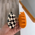 Close-up of heart-shaped hair claw clip with orange and checkered pattern and metal spring - Contrast Color / Checkerboard Orange Contrast