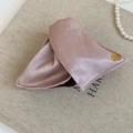 Detailaufnahme einer rosa Satin-Haarklammer mit goldenem Knopf und graviertem Text - Rosa
