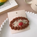 Vue détaillée d'une pince à cheveux tricotée main avec motif de fraise sur carte cadeau - Gâteau à la fraise café