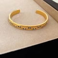 Détail du bracelet jonc Evil Eye doré avec cils gravés sur plateau à bijoux - Bracelet Jonc Ouvert Mauvais Œil Vintage Doré