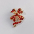 Golden four-leaf clover brooch with sparkling red rhinestones and ribbon detail - Red Clover