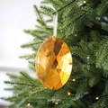 Golden multifaceted acrylic gem Christmas tree ornament with 13cm length hanging on a branch - Oval Gemstone / Gold