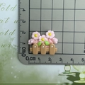 Macro shot of miniature brown resin fence with pink flowers and green leaves on a scale - Light Pink Flower Fence