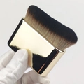 Detailed view of wide flat foundation brush with golden handle and black bristles - Gold