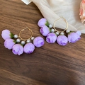 Detalle de pétalos de rosa púrpuras y perlas blancas en un pendiente de aro dorado - Morado