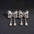 Macro shot of sparkling silver bow earrings with crystal water drop tassels on black texture - Bowknot Tassel Earrings (Silver Pin) / Silver