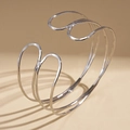 Detail van de zilveren open armband met gehamerde textuur en golvend lijnontwerp - Zilver