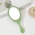 Green vintage hand mirror with intricate floral carvings and a portable handle - Light Green