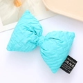Detail of light blue quilted leather bow accessory with diamond texture and small label - Blue