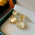 Close-up of golden geometric earrings with yellow cat eye stones in a jewelry box - Gold Double Circle Earring