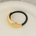 Minimalist golden metal hair tie with black elastic band on a white ceramic tray - Single Layer Arc KC Gold