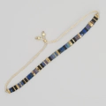 Detail eines böhmischen gewebten Armbands mit mattem Schwarz, Goldperlen und verstellbarem Band - Schwarz Gold Irisierendes Blau