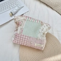 Detail der floralen gesteppten Kosmetiktasche mit Markenetikett und weicher Stoffstruktur - Rosa Karomuster