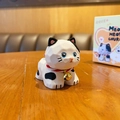 Cartoon low poly kattenbeeldje met zwarte vlekken en gouden bel op houten tafel - Meow Meow Church Houtsnijwerk - Koekat