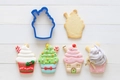 Blue cupcake-shaped cookie cutter with finished Christmas house and snowman biscuits - 7x5cm
