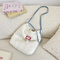 Dettaglio borsa bianca trapuntata a cuore con tracolla blu su sfondo in peluche - Bianco Crema