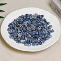 Polished natural blue sodalite tumbled stone chips displayed in a white plate - Blue Speckled Quartz (7-9mm) 100g