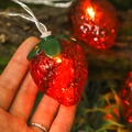 Warm glowing red strawberry LED string light with green leaf base held in hand - Strawberry / 1.5M 10LEDs (2AA Constant)
