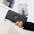 Close-up of black lychee leather wallet with metal studs and skull detail held by hand - Black
