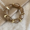 Dettaglio dei grani in acrilico ambrato con glitter dorati e distanziatori in metallo - Bracciale - Caffè Chiaro