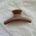 Detail view of a brown amber resin hair claw clip with a glossy finish on white paper - Beige Coffee