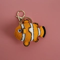 Porte-clés poisson-clown fait main en crochet orange et blanc sur un fond rose doux - Poisson-clown Orange