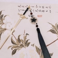 Close-up of golden sword hair pin with blue silk tassel and red bead details - Sword Tassel-Gold Black Blue