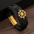 Détail macro d'un bracelet en cuir tressé noir pour homme avec gouvernail doré et fermoir - Noir + Or