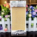 Close-up of golden acrylic crystal rhinestone stickers with card packaging for DIY decor - 6mm / Gold