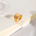Dettaglio dell'anello in acciaio placcato oro con trama a coccodrillo tra le pagine - Anello Aperto con Trama a Scacchi