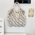 Close-up of cream canvas tote bag with cute animal prints and woven handles - Skating Dog