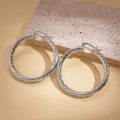 Dettaglio di grandi orecchini a cerchio a spirale argento con trama in metallo ritorto - Argento
