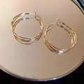 Macro shot of gold multi-layered textured hoop earrings reflecting on a mirror surface - Triple Stacked Hoop Style / Gold